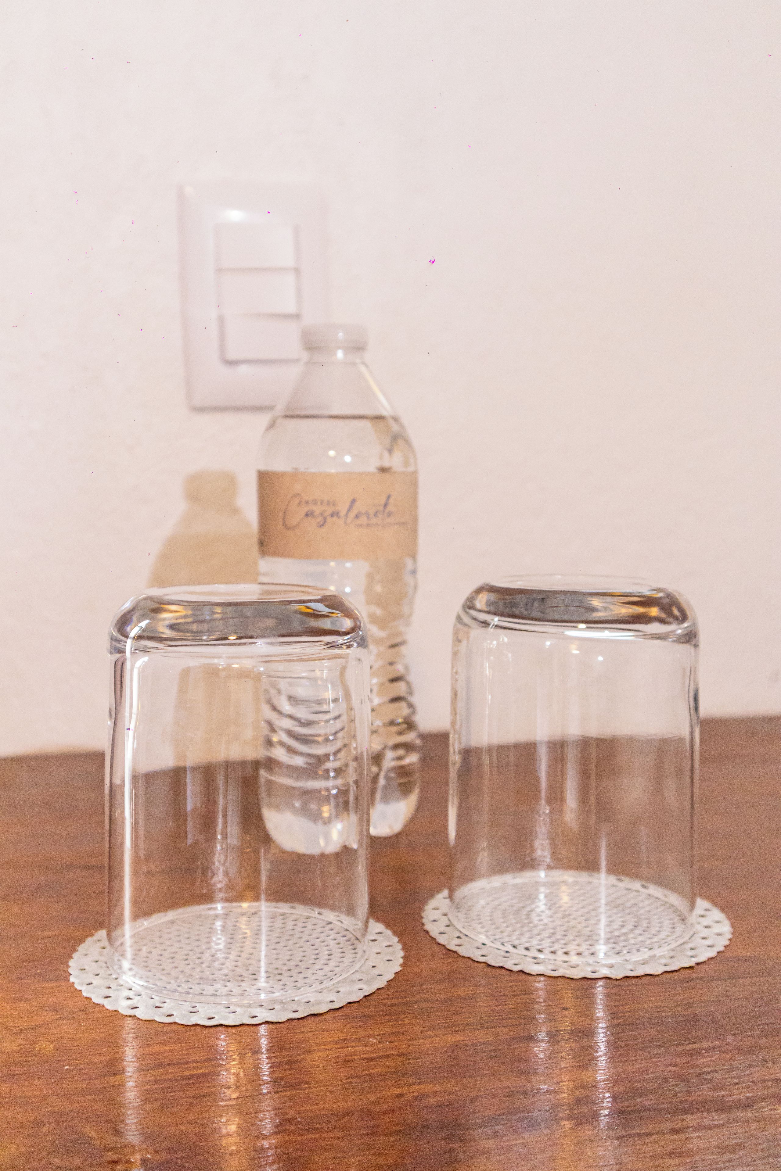 Deux verres en verre transparent, dotés d’une base texturée, posés sur une table en bois.