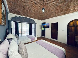 Ein Zimmer mit zwei Betten, einem Fernseher und einer Holzbalkendecke.