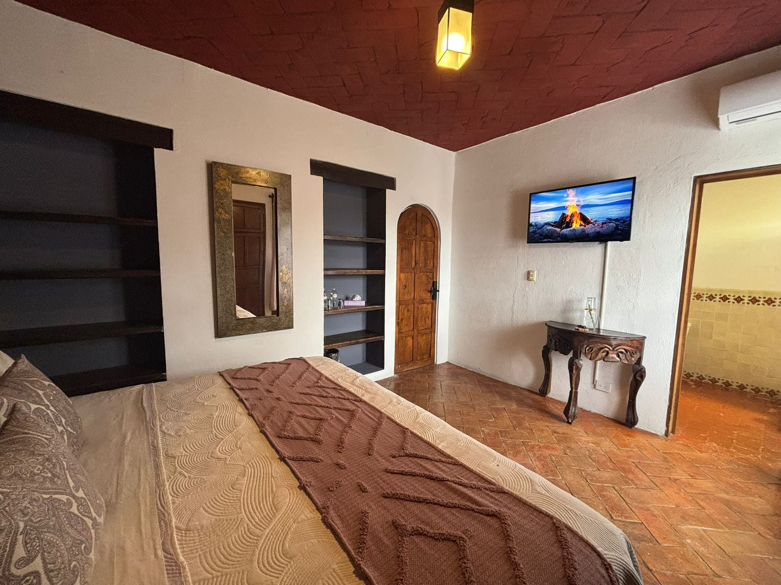 Een slaapkamer met een bed, een televisie, een houten deur en een plankunit.