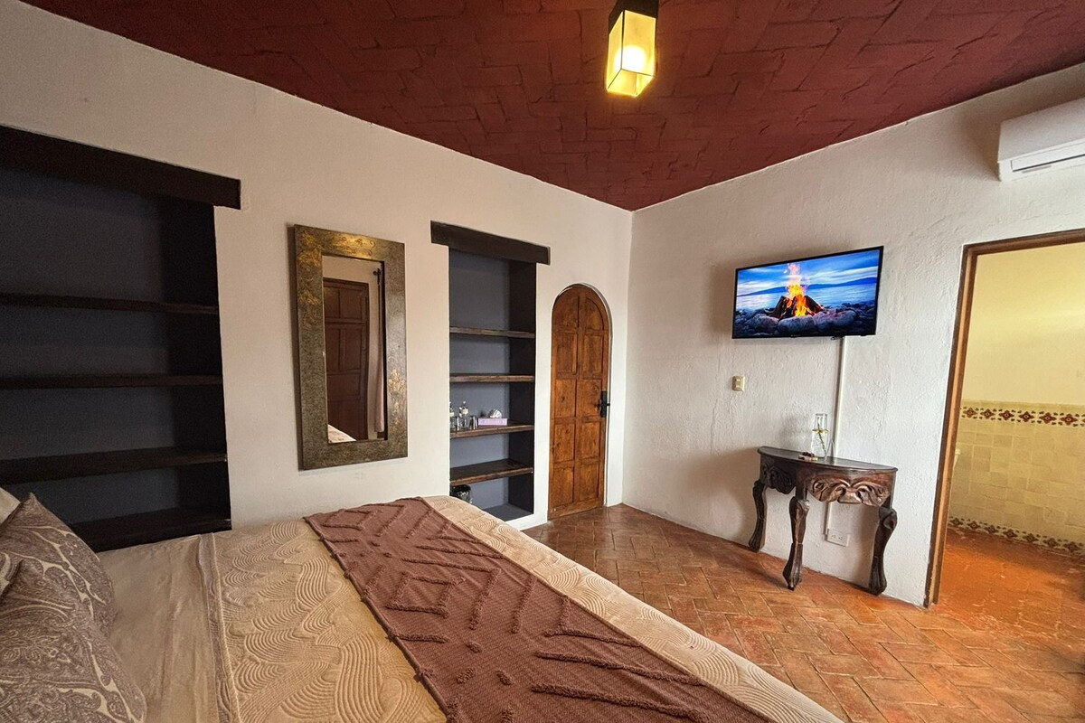 Ein Schlafzimmer mit Bett, Fernseher, Holztür und einer Regalwand.