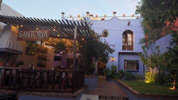 Un restaurante llamado Santoria Restaurante con terraza y zona ajardinada.