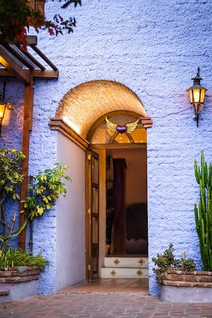A building entrance with a brick archway, a decorative emblem above the door, and a wall-mounted light fixture. - Santoria Restaurante & Hotel (San Miguel de Allende)