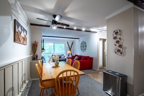 Ein Essbereich mit Holztisch und -stühlen, einer roten Couch und einem Deckenventilator.