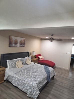 A bedroom with a bed, nightstands, a red chair, a ceiling fan, and a painting on the wall. - Modern cabin style home in the heart of San Antonio. (San Antonio)