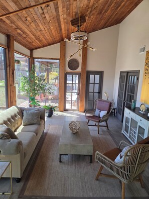 A spacious living area with a wooden ceiling, a sofa, a chair, a coffee table, and a view of the outdoors. - Modern cabin style home in the heart of San Antonio. (San Antonio)
