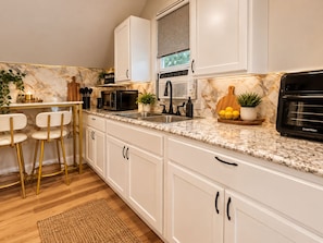A modern kitchen with white cabinets, a granite countertop, a black oven, and a window above the sink. - Just Minutes From Downtown, Cleveland Clinic & University Circle, Free Parking (Cleveland)