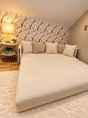 Ein Schlafzimmer mit einem großen Bett, einem runden Beistelltisch, einer Lampe und einer Wand mit marmorartigem Muster.