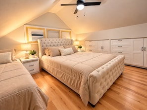 Ein Schlafzimmer mit einem großen Bett, Nachttischen, einem Deckenventilator und eingebauten Kleiderschränken.