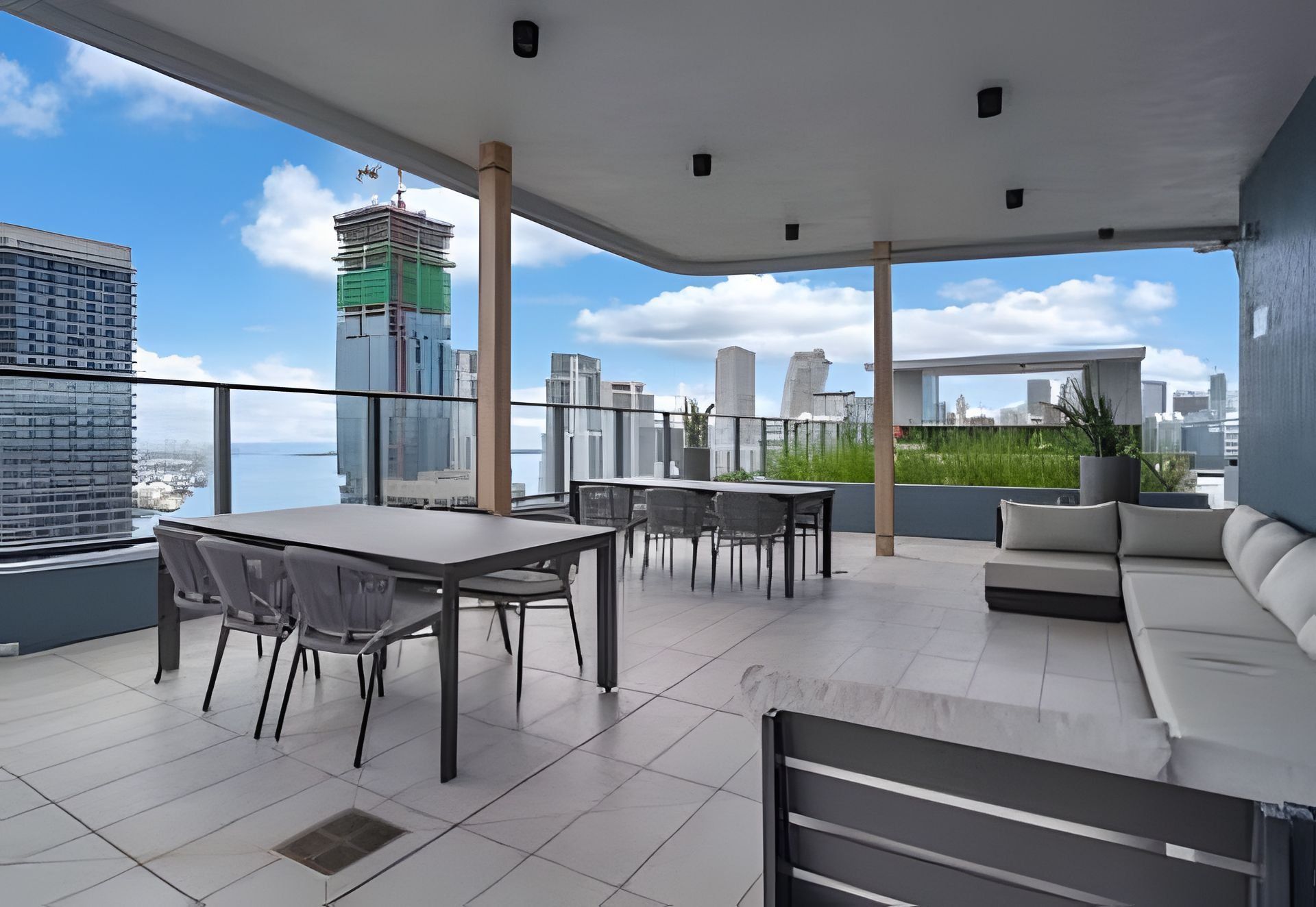 Eine Dachterrasse mit Essbereich, Sitzgelegenheiten und Blick auf die Stadtlandschaft.