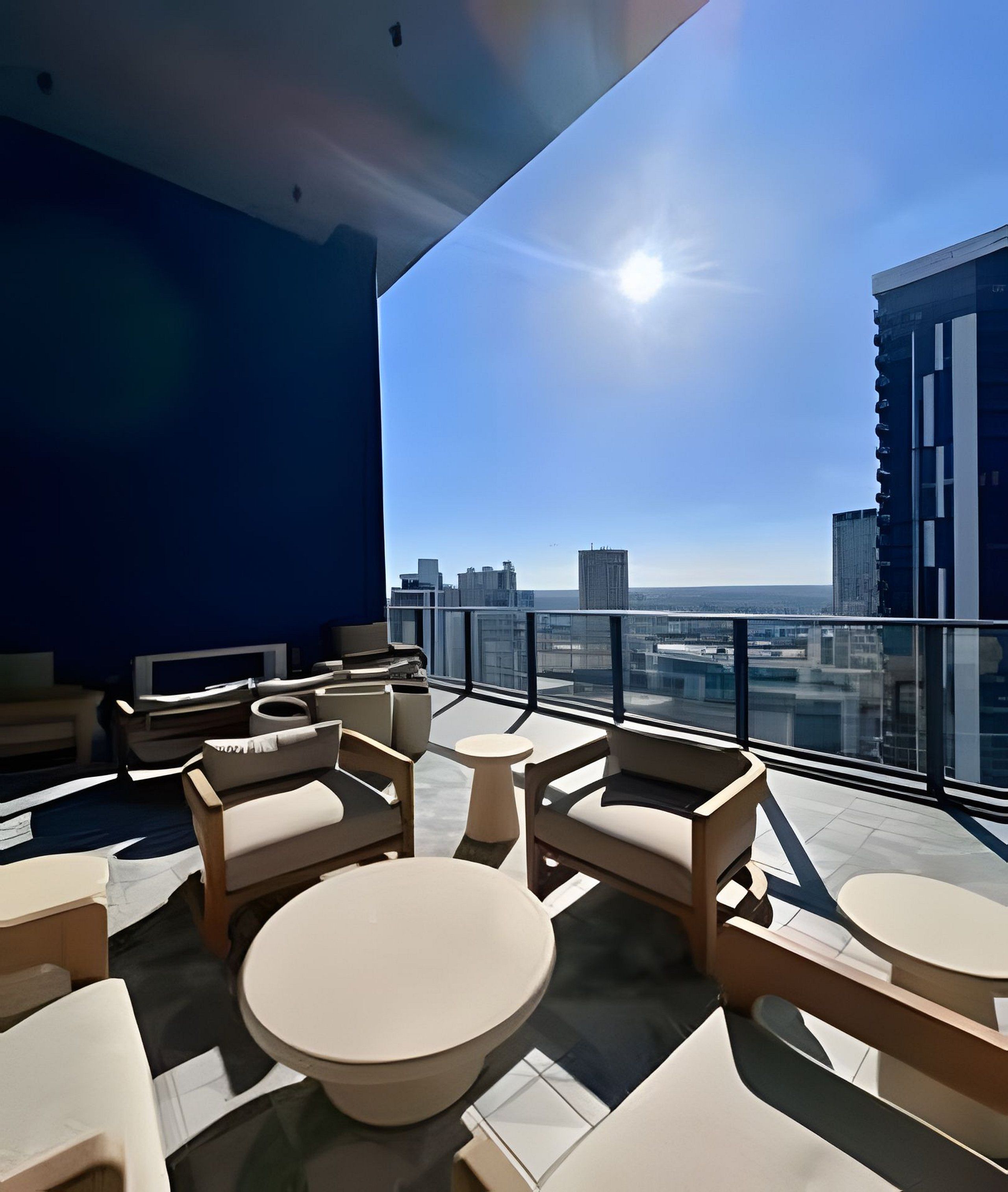 A modern rooftop lounge with a city view, featuring contemporary furniture and a glass railing.