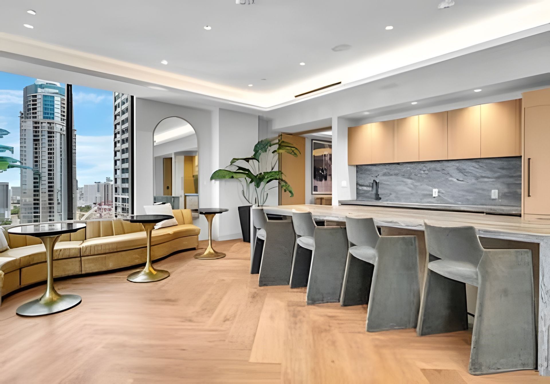 Una cocina moderna con encimera de mármol, asientos tipo barra y vistas a la ciudad.