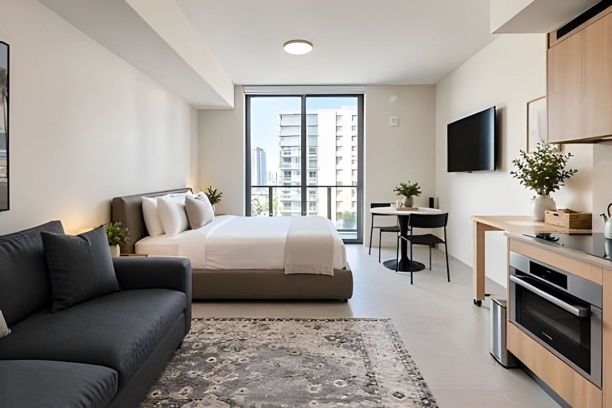 Quarto moderno com cama, sofá, mesa de jantar e televisão.