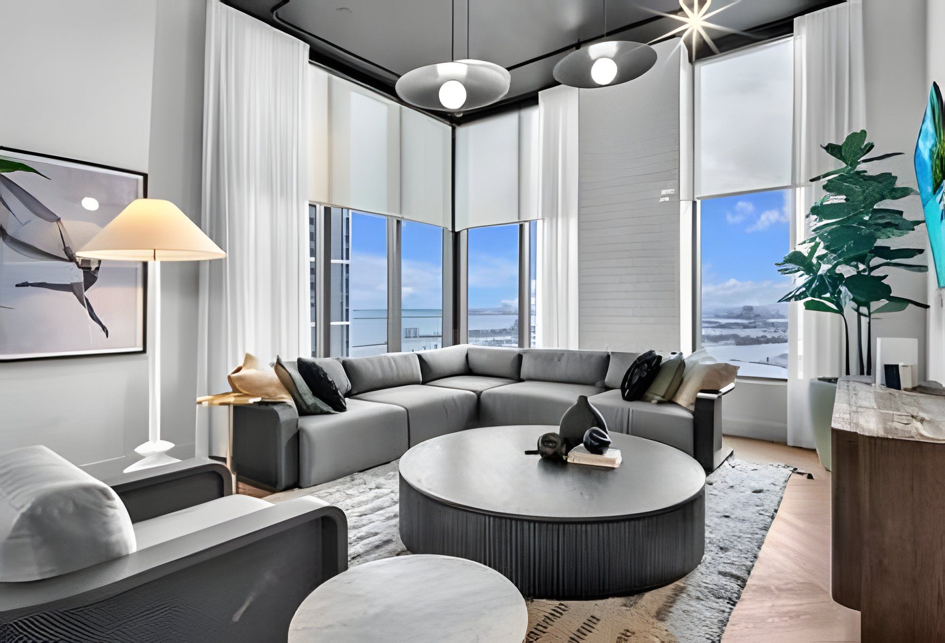 A modern living room with a sectional sofa, a round coffee table, and a large window offering a view of the cityscape.