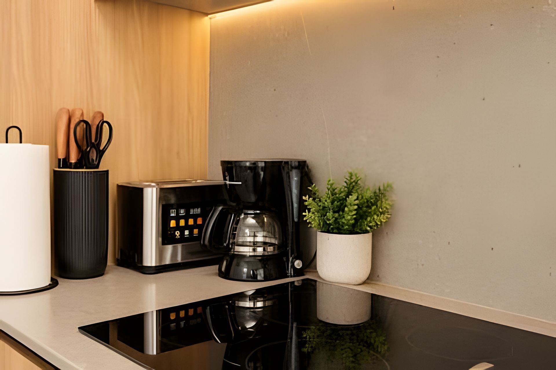 A modern kitchen with a built-in stove, a coffee maker, and a potted plant.