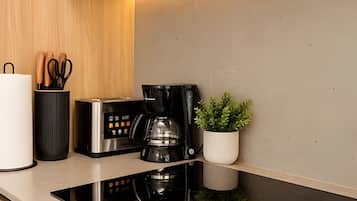 A modern kitchen with a built-in stove, a coffee maker, and a potted plant.
