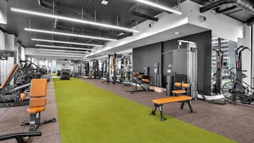 Academia com diversos equipamentos de exercício, grama sintética verde e design moderno.