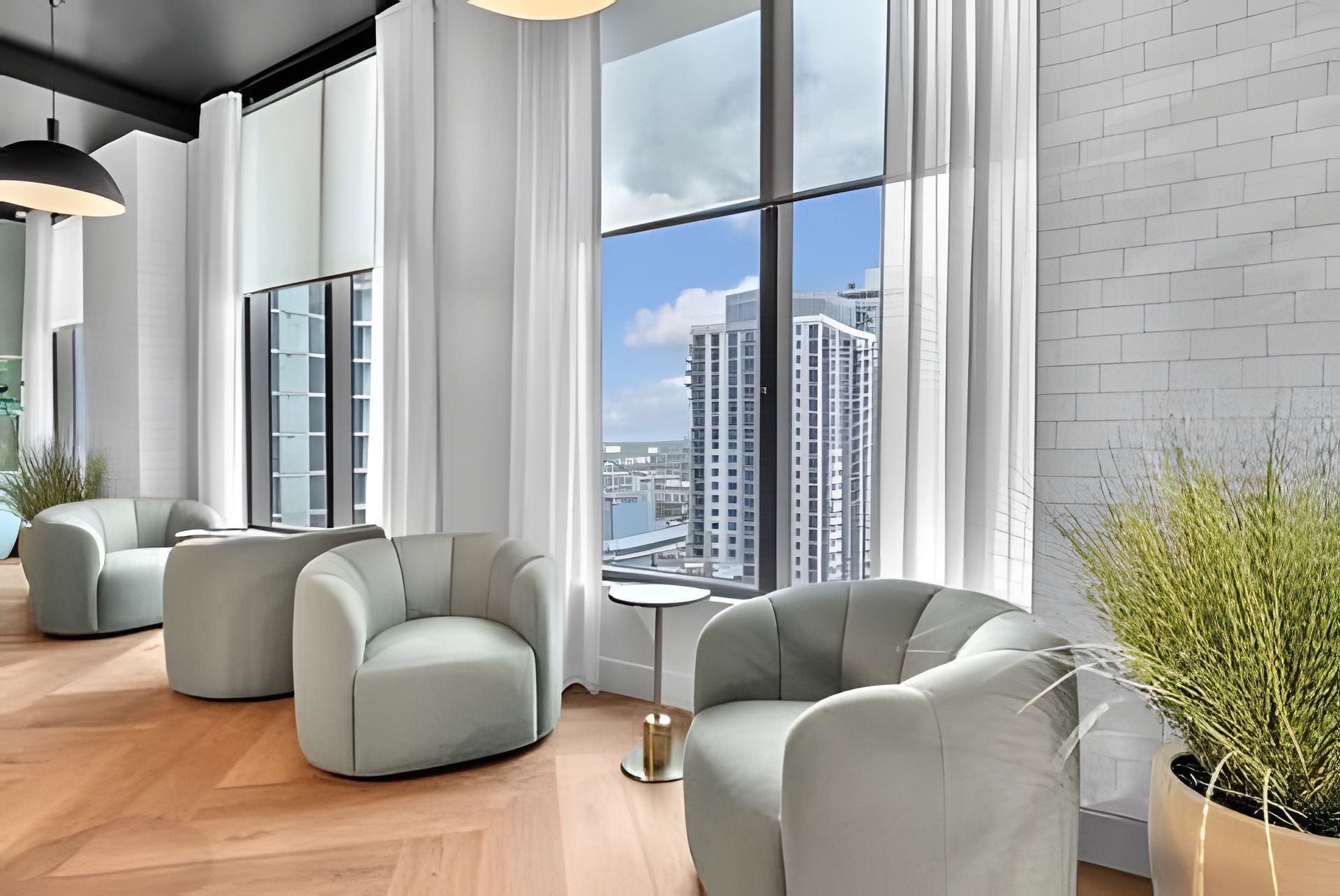 A modern interior with large windows, a view of high-rise buildings, and a seating area with a small table.