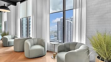 A modern interior with large windows, a view of high-rise buildings, and a seating area with a small table.