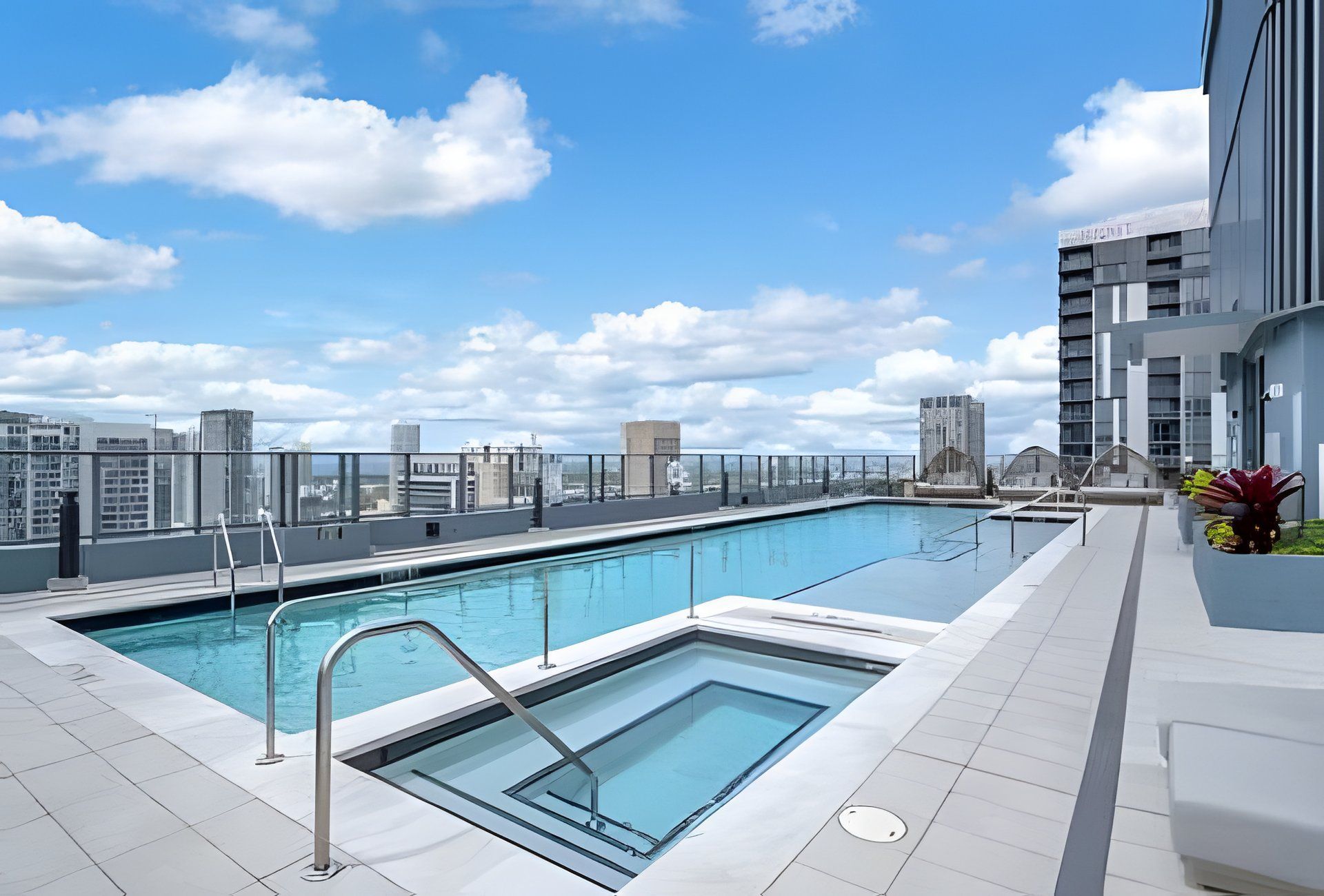 A rooftop swimming pool with a city view, surrounded by modern buildings.