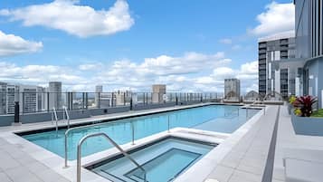 A rooftop swimming pool with a city view, surrounded by modern buildings.