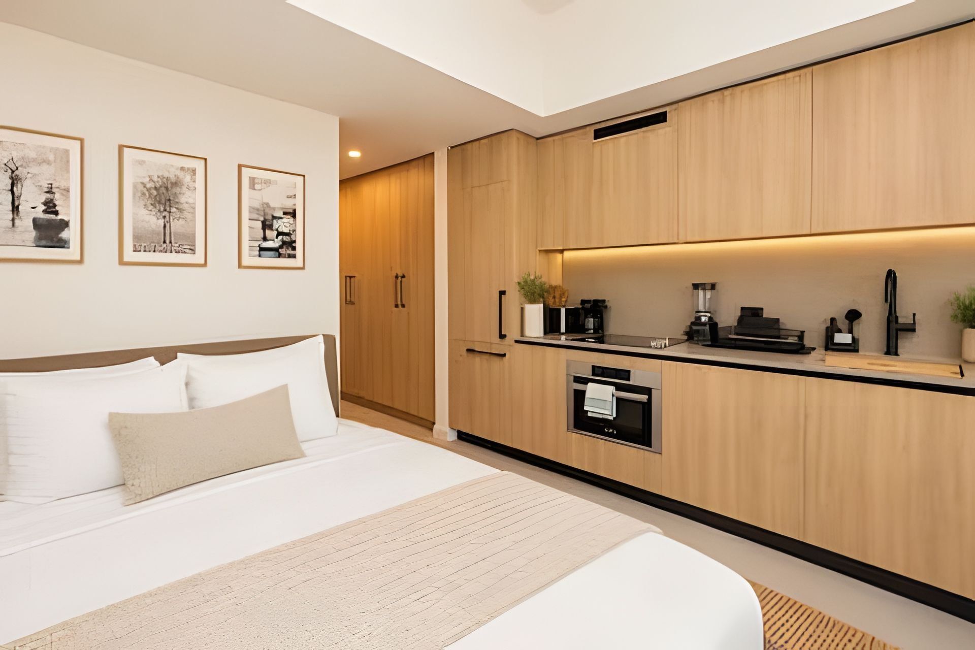 Una habitación de hotel moderna con una cama, kitchenette y obras de arte en la pared.