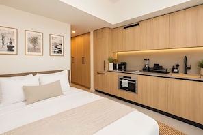 Una habitación de hotel moderna con una cama, kitchenette y obras de arte en la pared.