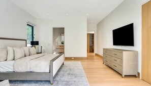 A modern bedroom with a bed, bedside table, lamp, and a TV on the wall. - Brand new 2026 designer construction- Full privacy-Gym-Sauna-Hotel bar- Firepit. (East Hampton)