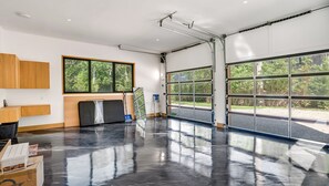 A spacious garage with large windows, a workbench, and a ladder. - Brand new 2026 designer construction- Full privacy-Gym-Sauna-Hotel bar- Firepit. (East Hampton)