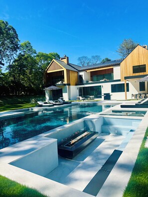 A modern house with a swimming pool, outdoor furniture, and a fire feature. - Brand new 2026 designer construction- Full privacy-Gym-Sauna-Hotel bar- Firepit. (East Hampton)