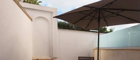 A patio with two chairs, a small table, and a large umbrella.