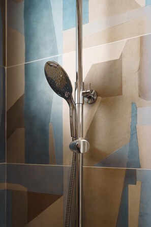 Een douche met een handdouche en een bedieningskraan aan de muur.