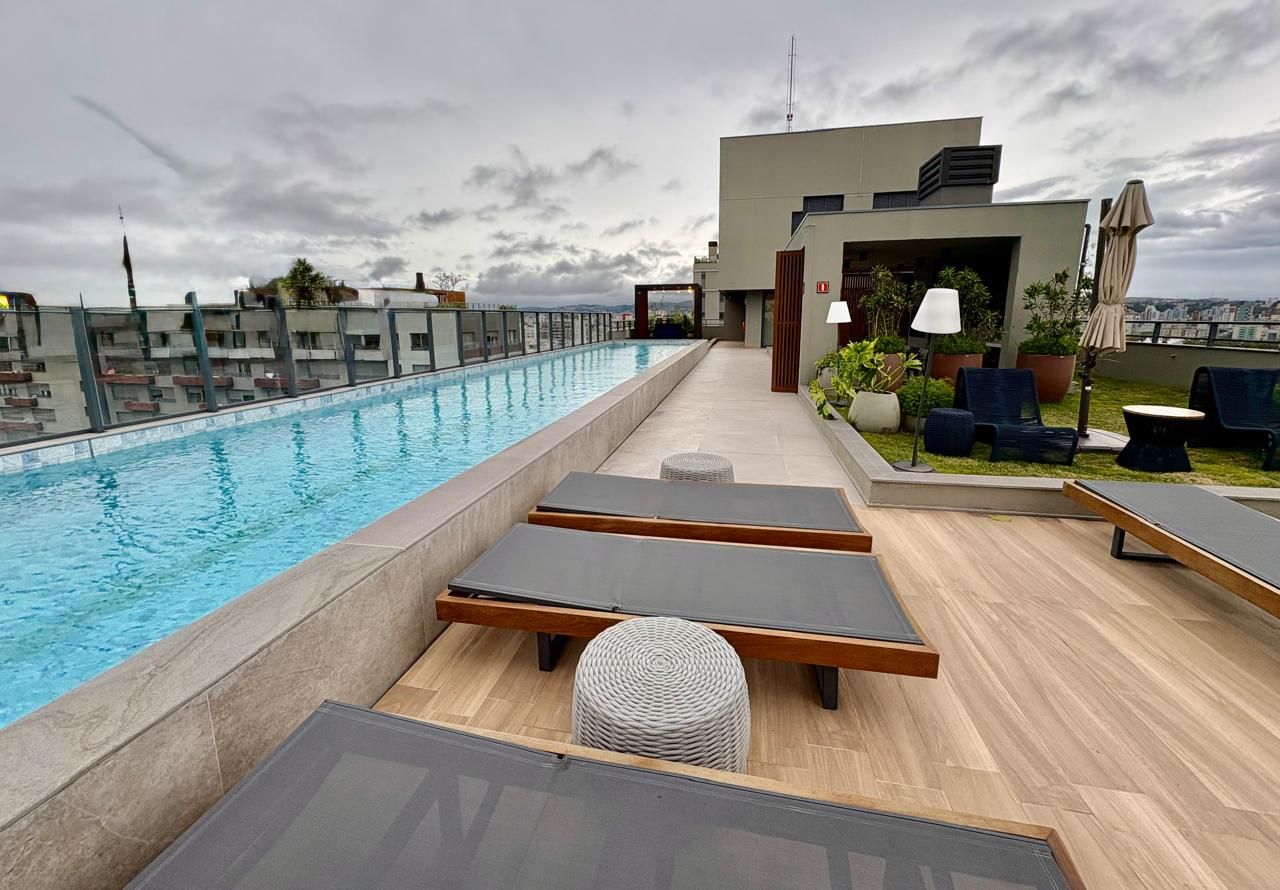 Une piscine sur le toit, avec des chaises longues, et un bâtiment moderne en arrière-plan.