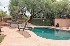 A backyard with a swimming pool, stone patio, and various plants. - Pool & Hot Tub / 4 BR 4 BA / Outdoor Living (Tucson)