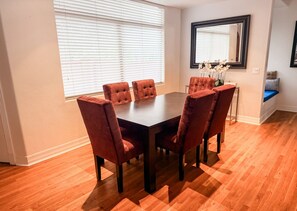 A dining area with a rectangular table and six chairs, a window with blinds, and a mirror on the wall. - Pool & Hot Tub / 4 BR 4 BA / Outdoor Living (Tucson)
