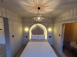 Ein modernes Schlafzimmer mit einem großen Bett, einer außergewöhnlichen Deckenleuchte und zwei Wandlampen.