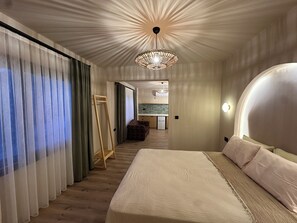 Une chambre moderne avec un grand lit, un dressing et une vue sur la cuisine.