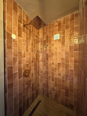 Eine Dusche mit gefliesten Wänden und einer Handbrause.
