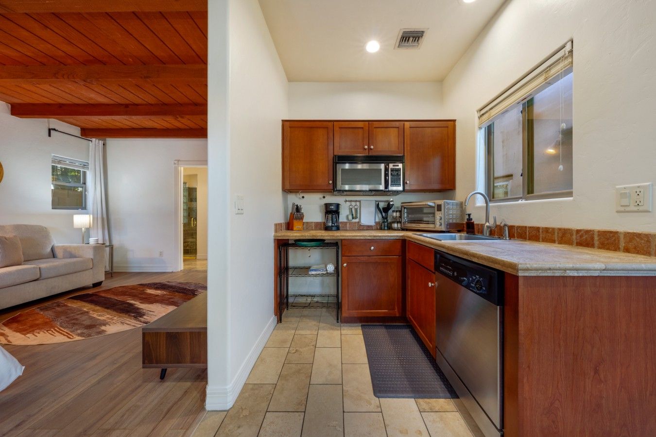 A compact kitchen with wooden cabinets, a microwave, and a dishwasher.