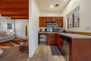 A compact kitchen with wooden cabinets, a microwave, and a dishwasher.
