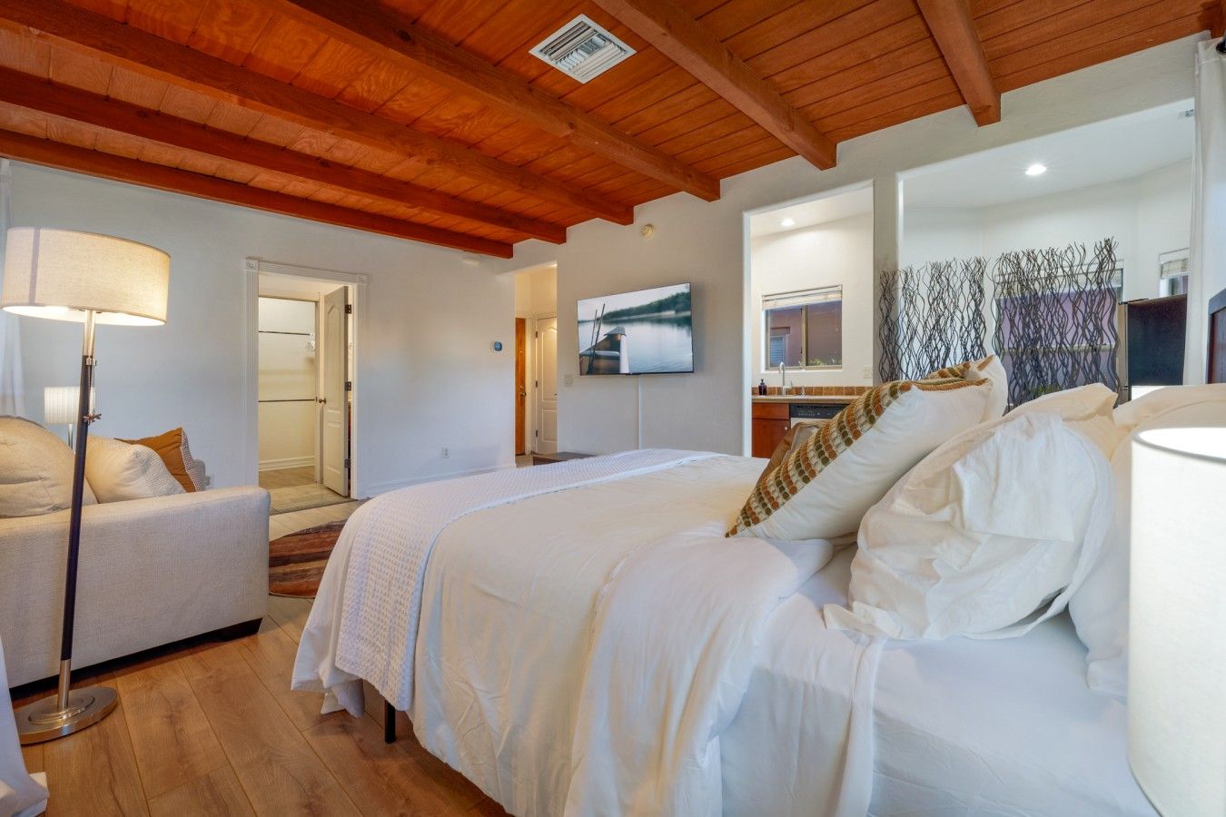 A bedroom with a large bed, a bedside table, a lamp, and a view of the bathroom.