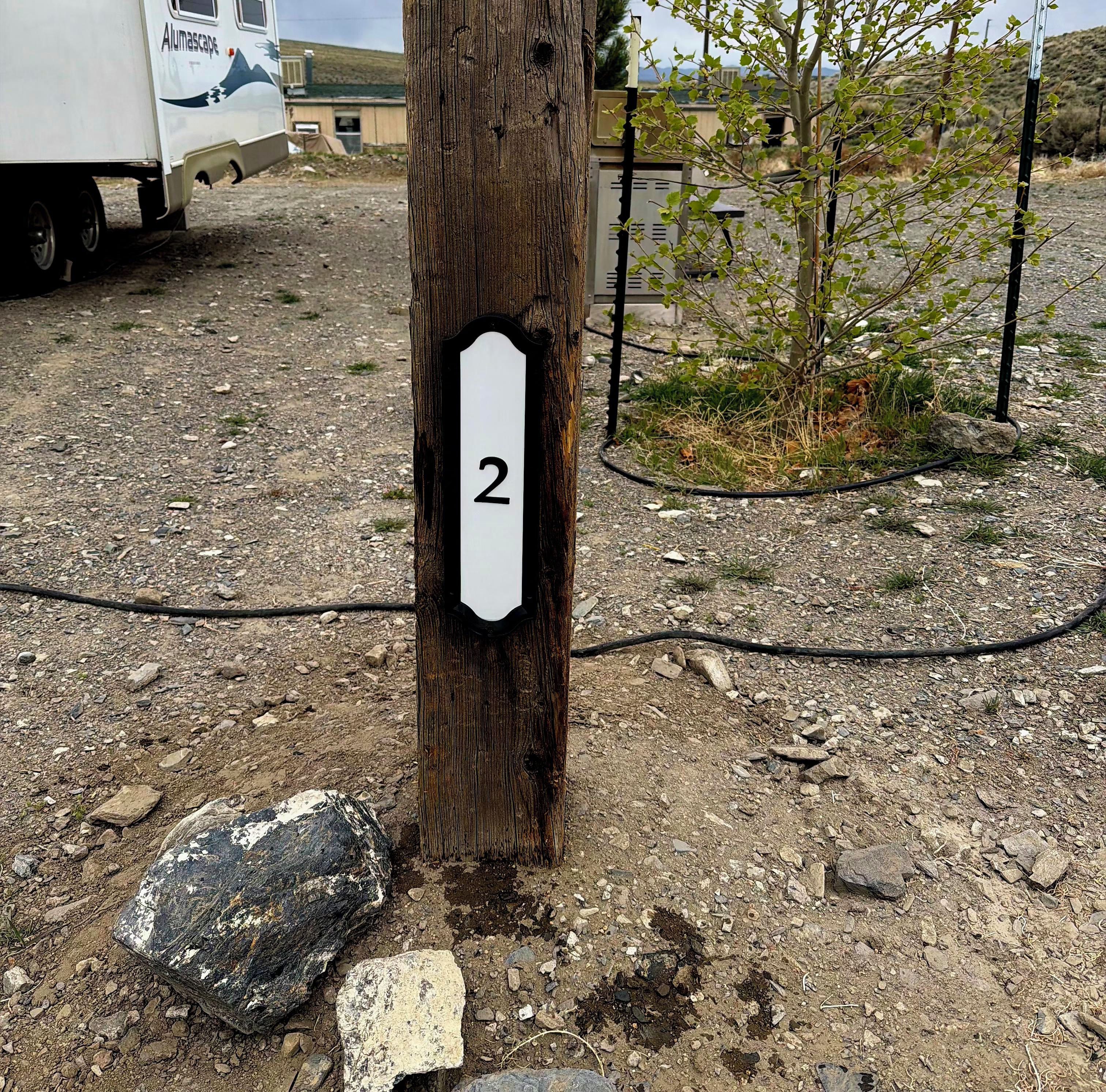 A wooden post with a white sign displaying the number '2'.