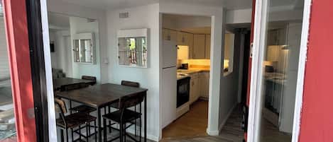 Un interior moderno con comedor, cocina y una puerta corredera con marco rojo.