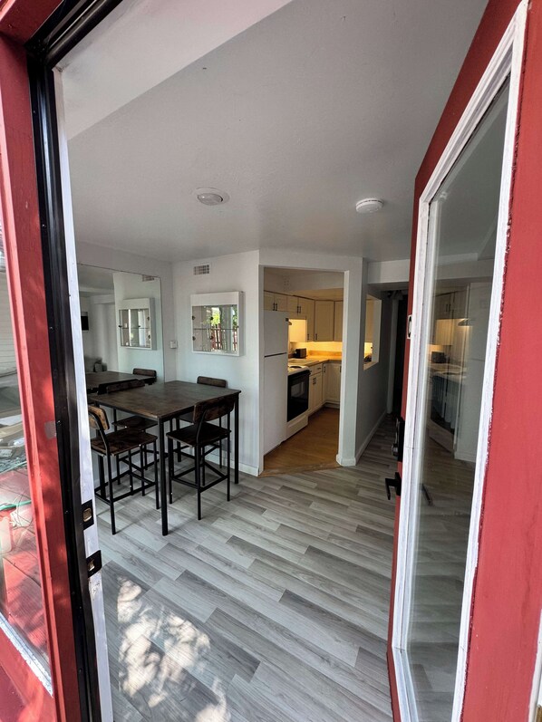 A modern interior with a dining area, kitchen, and a red-framed sliding door.