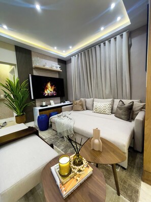 A modern living room with a flat-screen TV, a sofa, a coffee table, and a potted plant. - Luxury Apartment in Punta Cana: View from the Poll (Punta Cana)