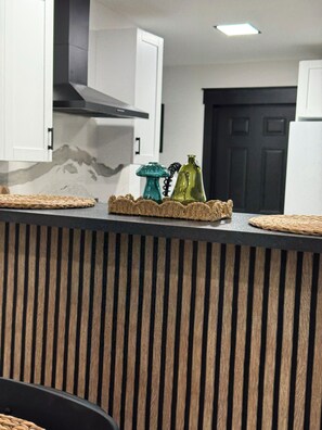 A kitchen counter with a woven placemat, a white cabinet, and a black door in the background. - Near Downtown Pickleball Paradise (Naples)