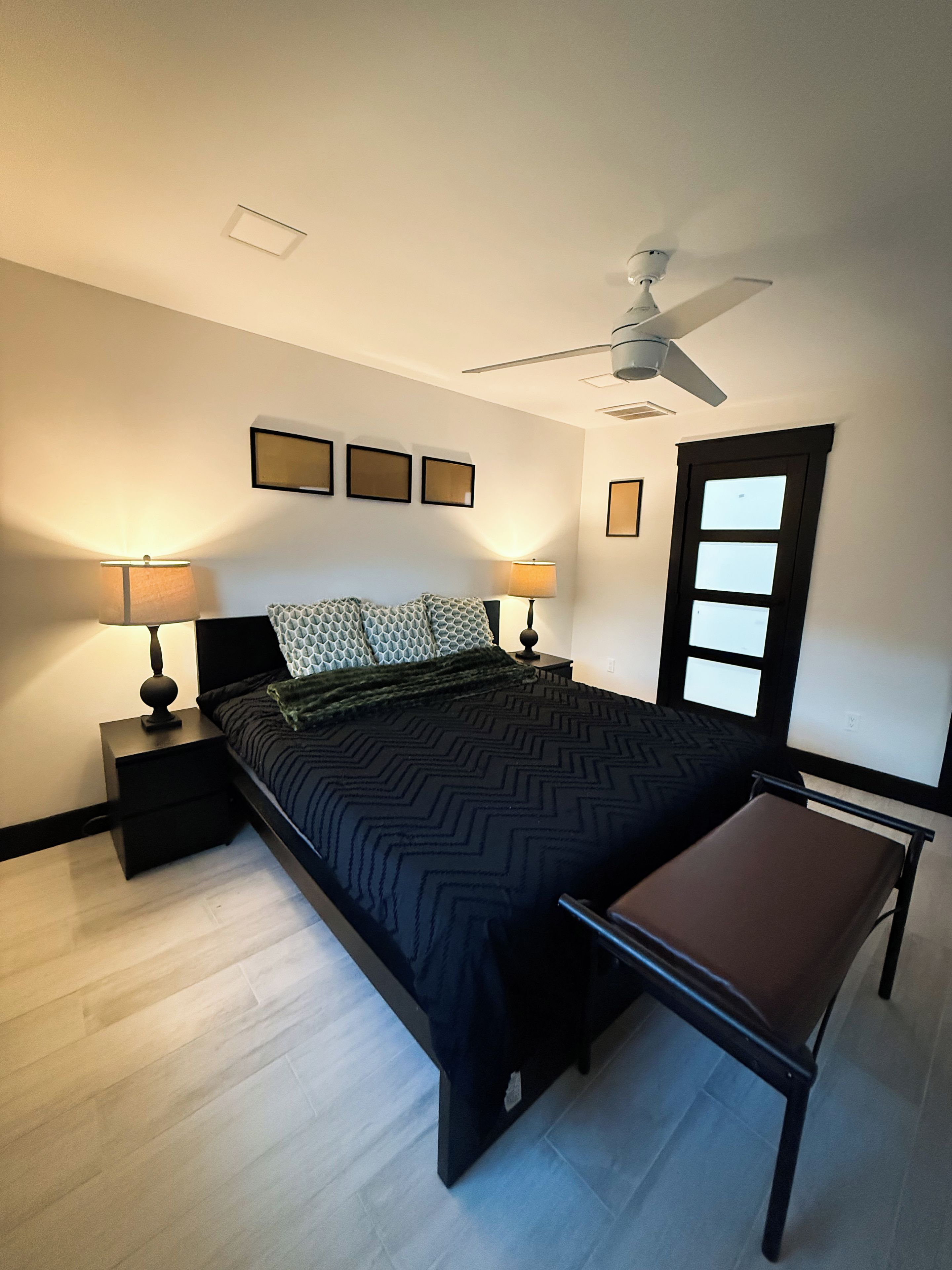 A bedroom with a bed, two bedside tables, a ceiling fan, and a window.