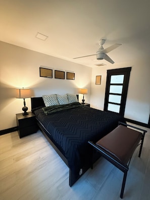 A bedroom with a bed, two bedside tables, a ceiling fan, and a window. - Near Downtown Pickleball Paradise (Naples)