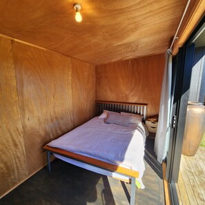 A single bed with a wooden headboard in a room with wooden walls and a sloped ceiling. - Surf & Fish Beach Retreat (Whangamatā)