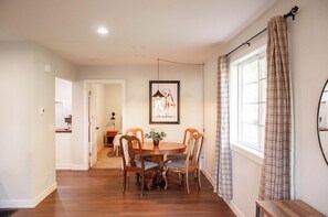 A dining area with a round wooden table, four chairs, a potted plant, and a framed picture on the wall. - Charming Crookston Cottage (Crookston)