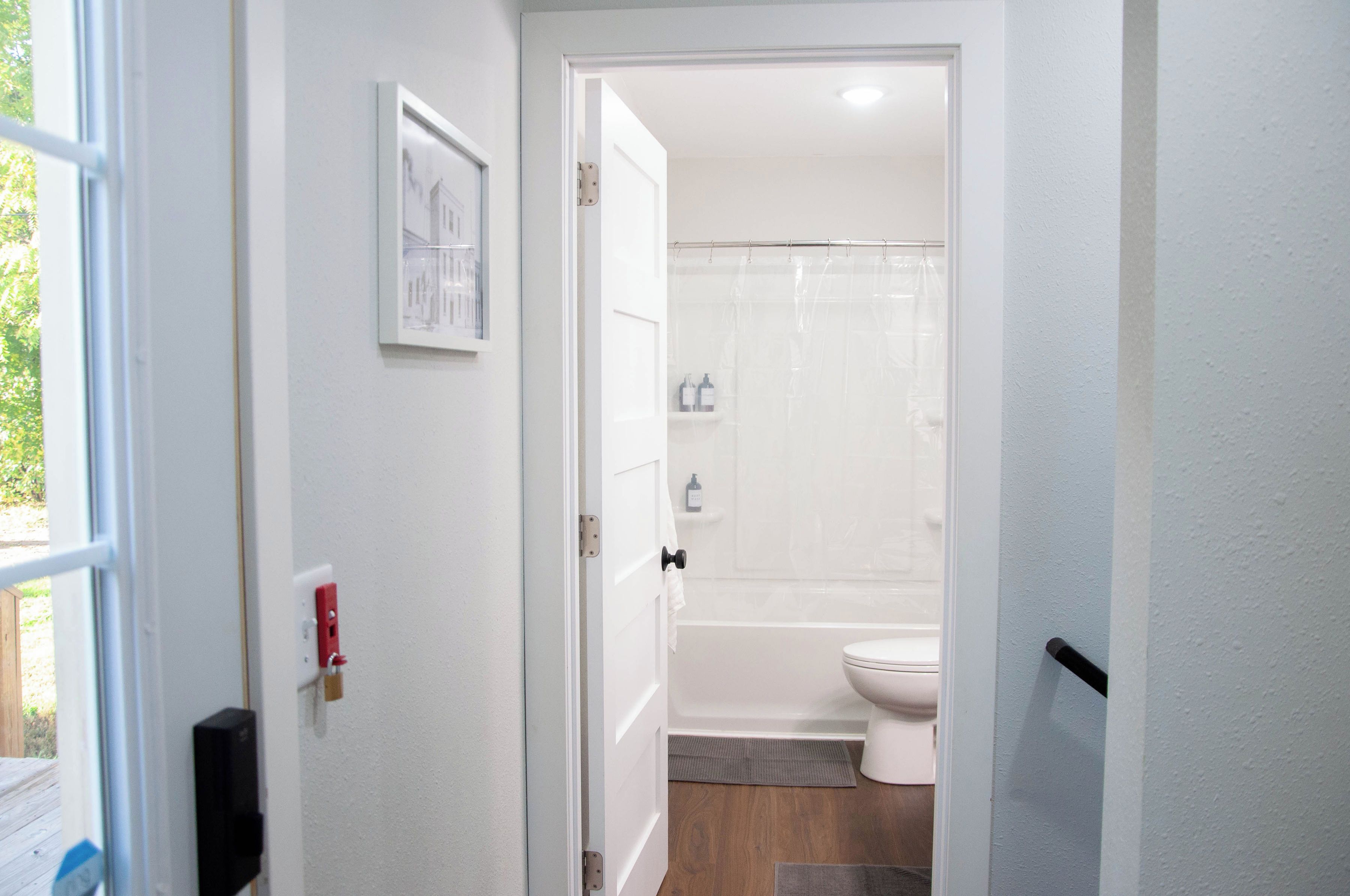 A bathroom with a toilet, shower, and a door leading to a hallway.